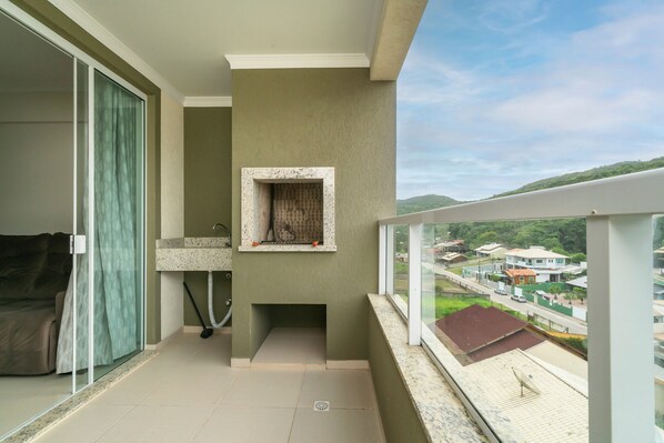 A balcony with a view of houses, a sink, and a window with a curtain.