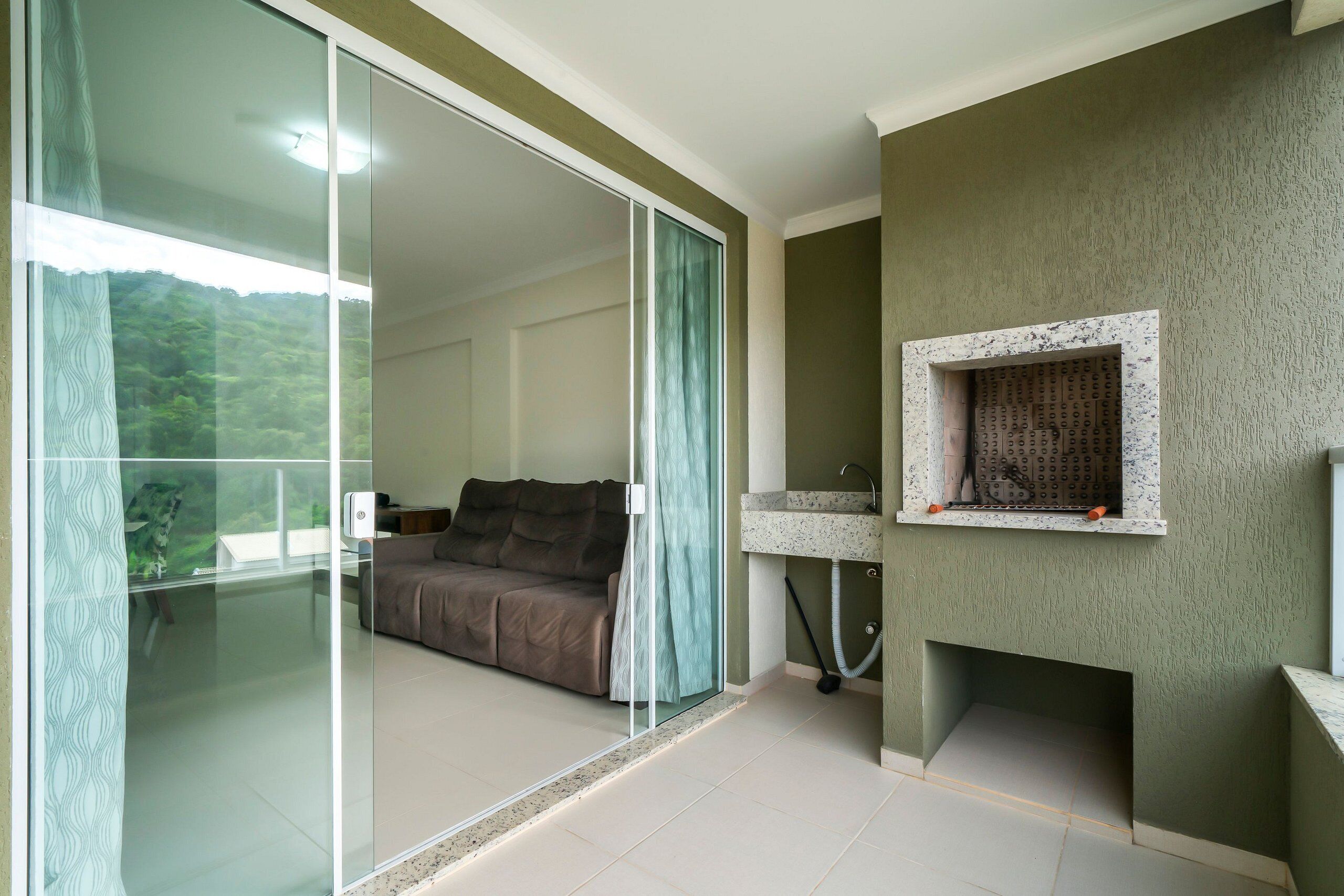 A room with a bed, a glass door leading to a balcony, a small sink, and a stone fireplace.