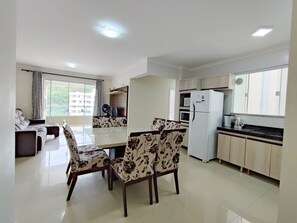 Una cocina moderna con comedor, refrigerador, microondas y un ventanal grande.