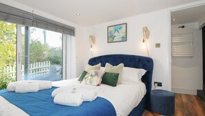Een slaapkamer met een groot bed, uitzicht op de omgeving en een witte muur met een schilderij.