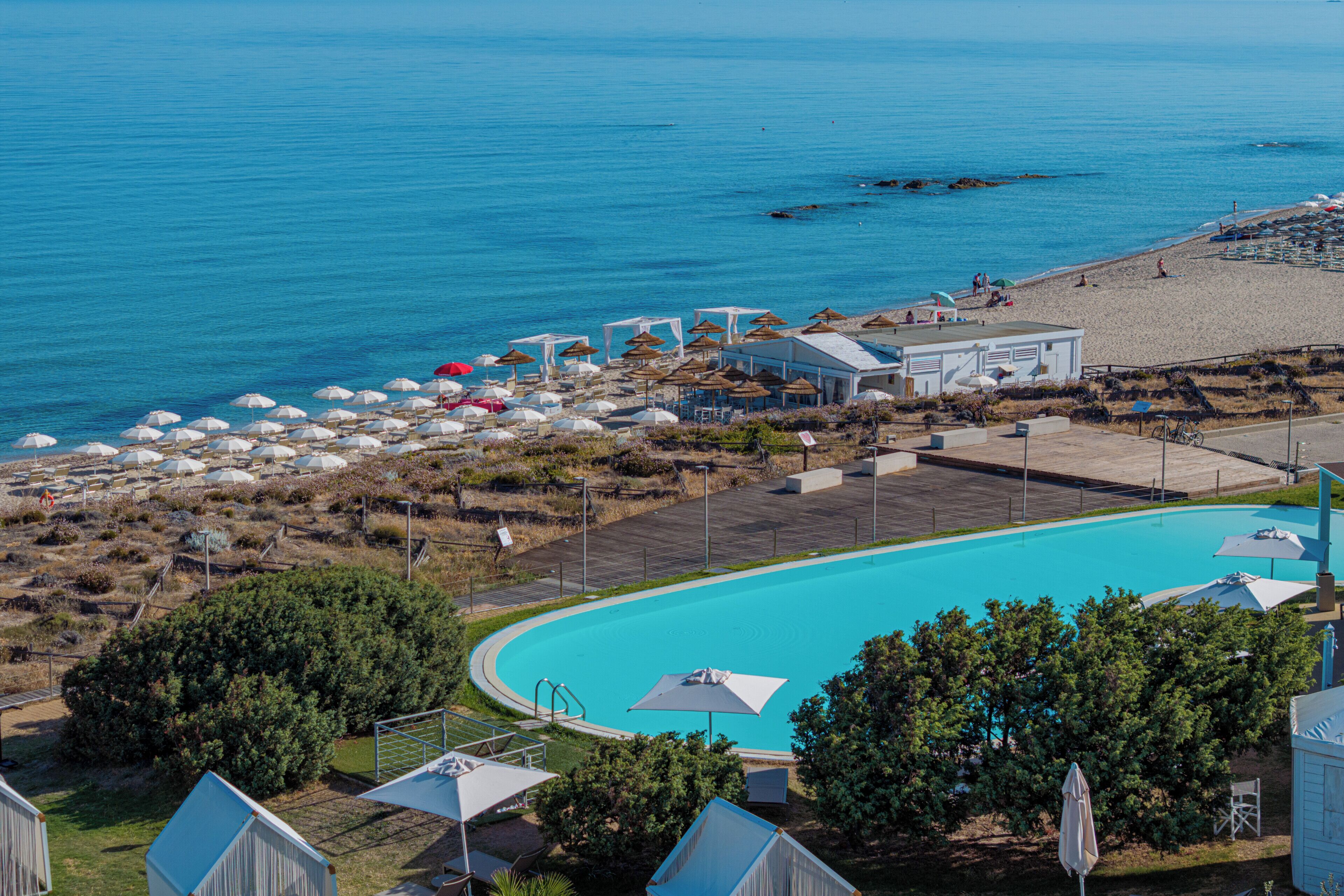 Un resort con piscina, sombrillas de playa y zona de playa.