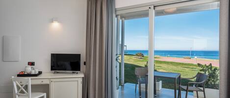 Habitación de hotel con escritorio, televisor y balcón con vista a la playa.