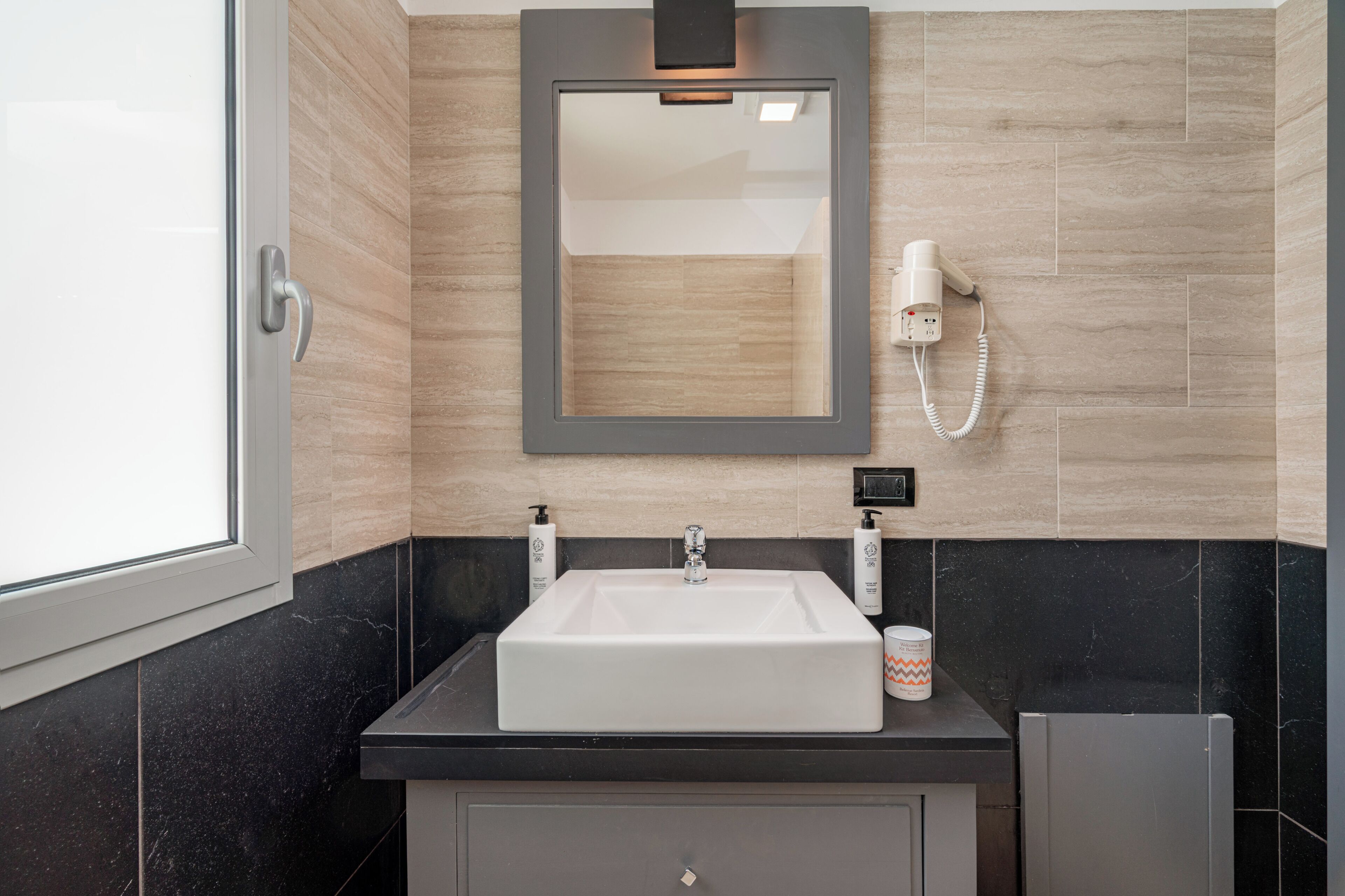 A bathroom with a white sink, a mirror, a hairdryer, and a towel dispenser.