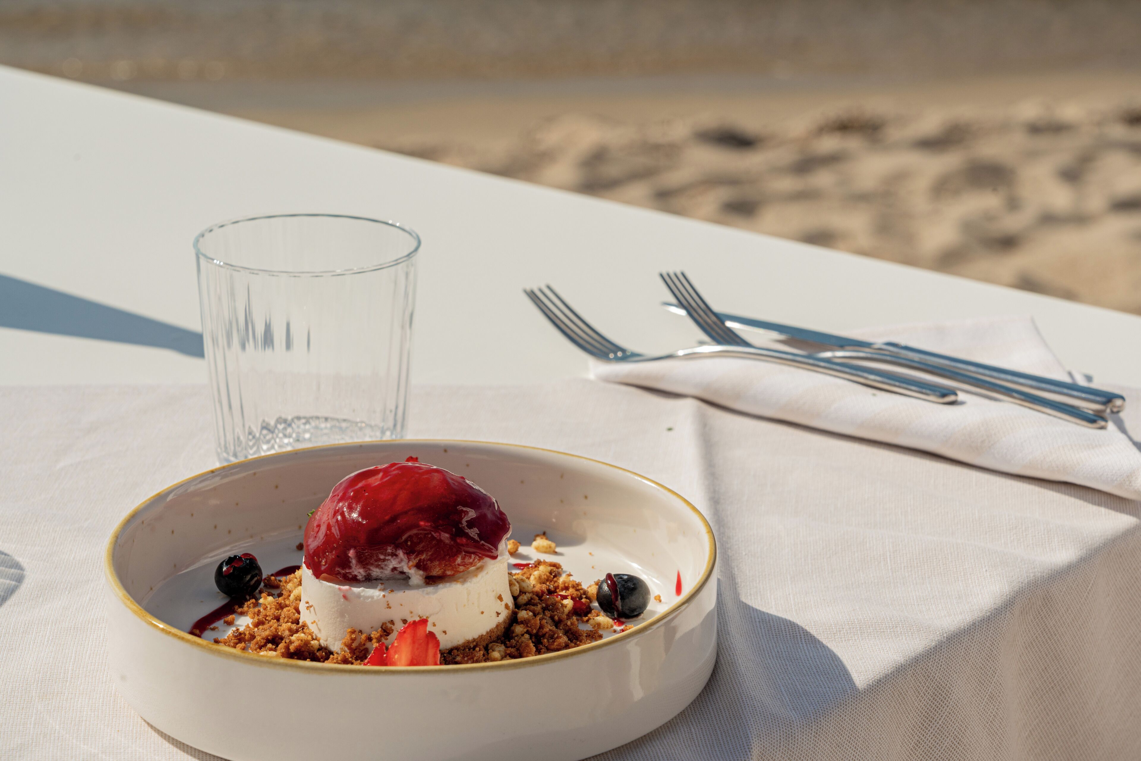 Un postre sobre una mesa con un vaso y cubiertos.