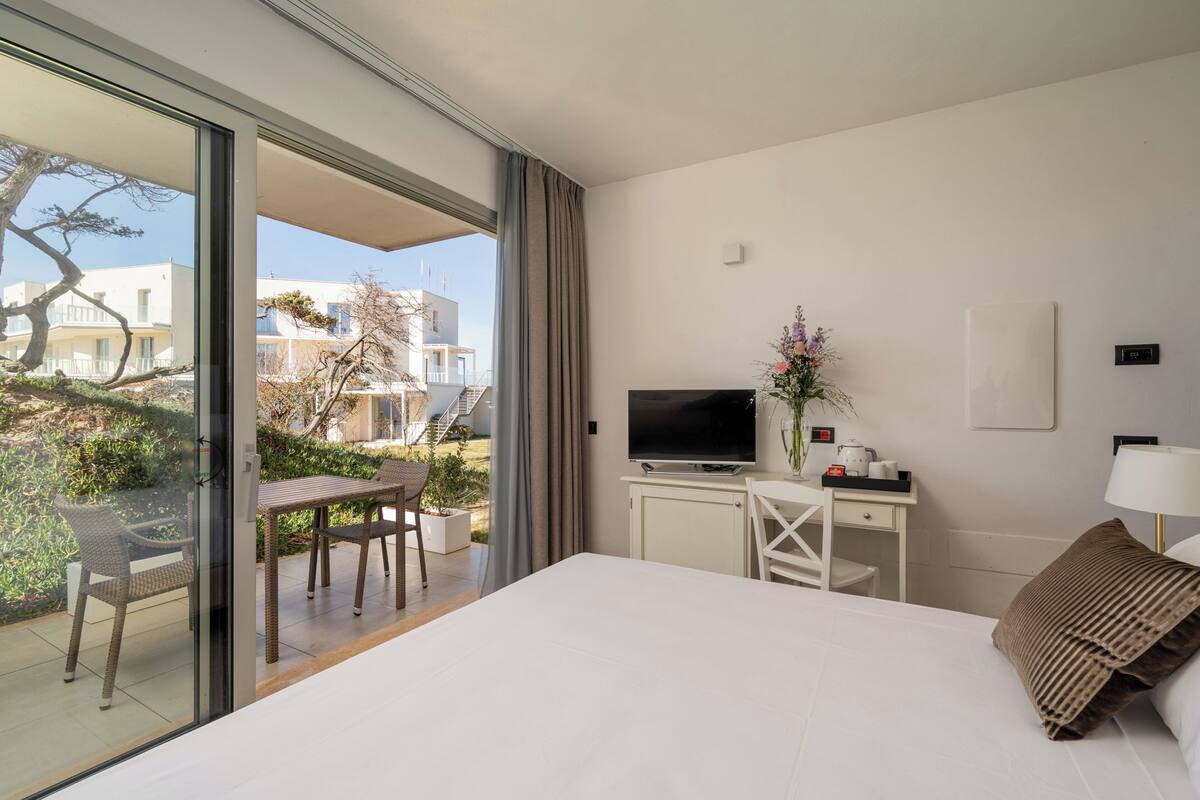 Une chambre d’hôtel avec un lit, un bureau avec une télévision, une chaise et une vue sur l’extérieur.