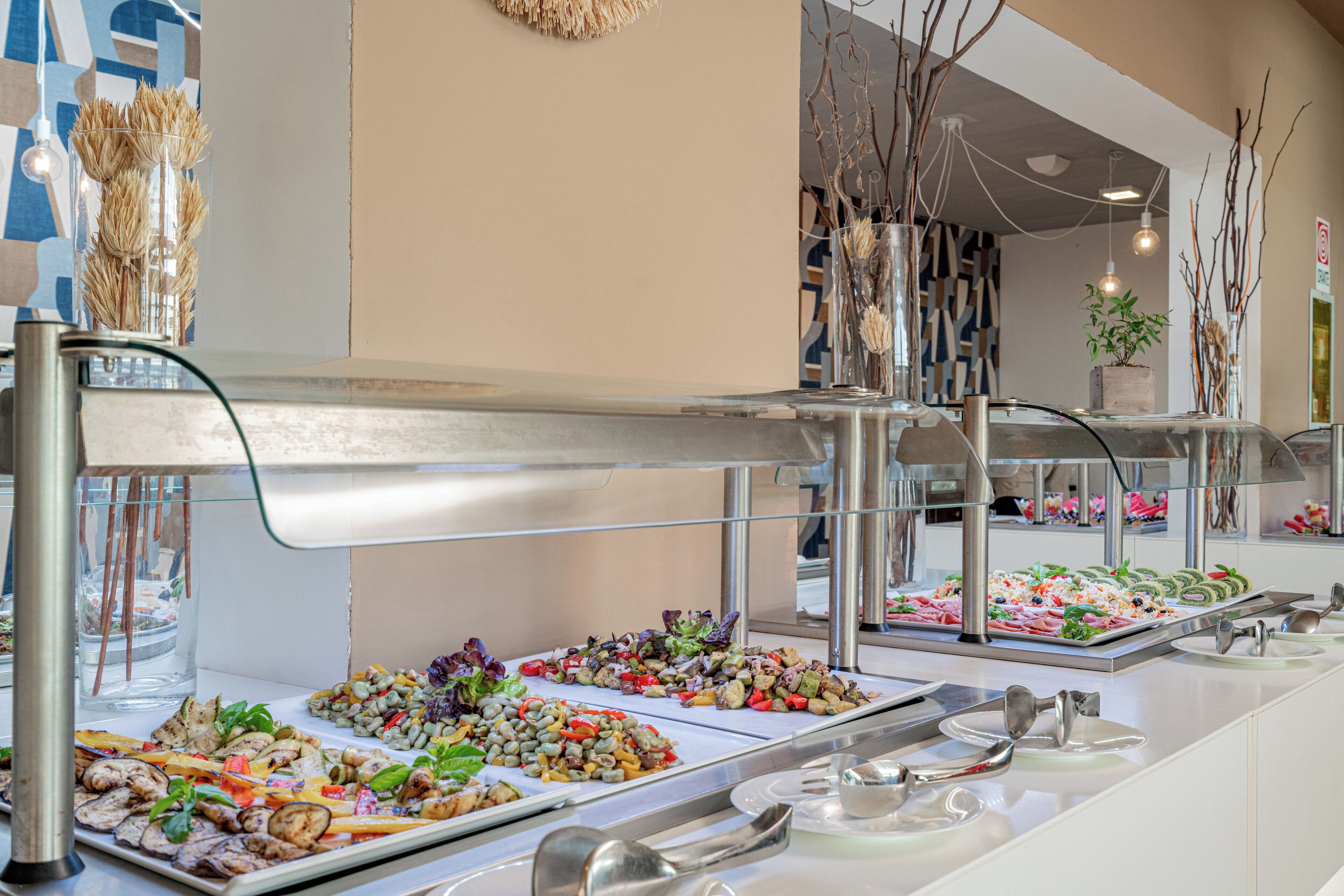 A buffet with various food options, a glass display case, and a decorative wall.