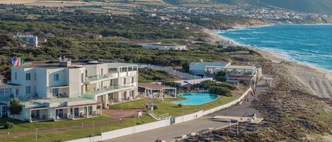 Un hotel frente al mar con piscina, varios balcones y vistas a la playa y al océano.