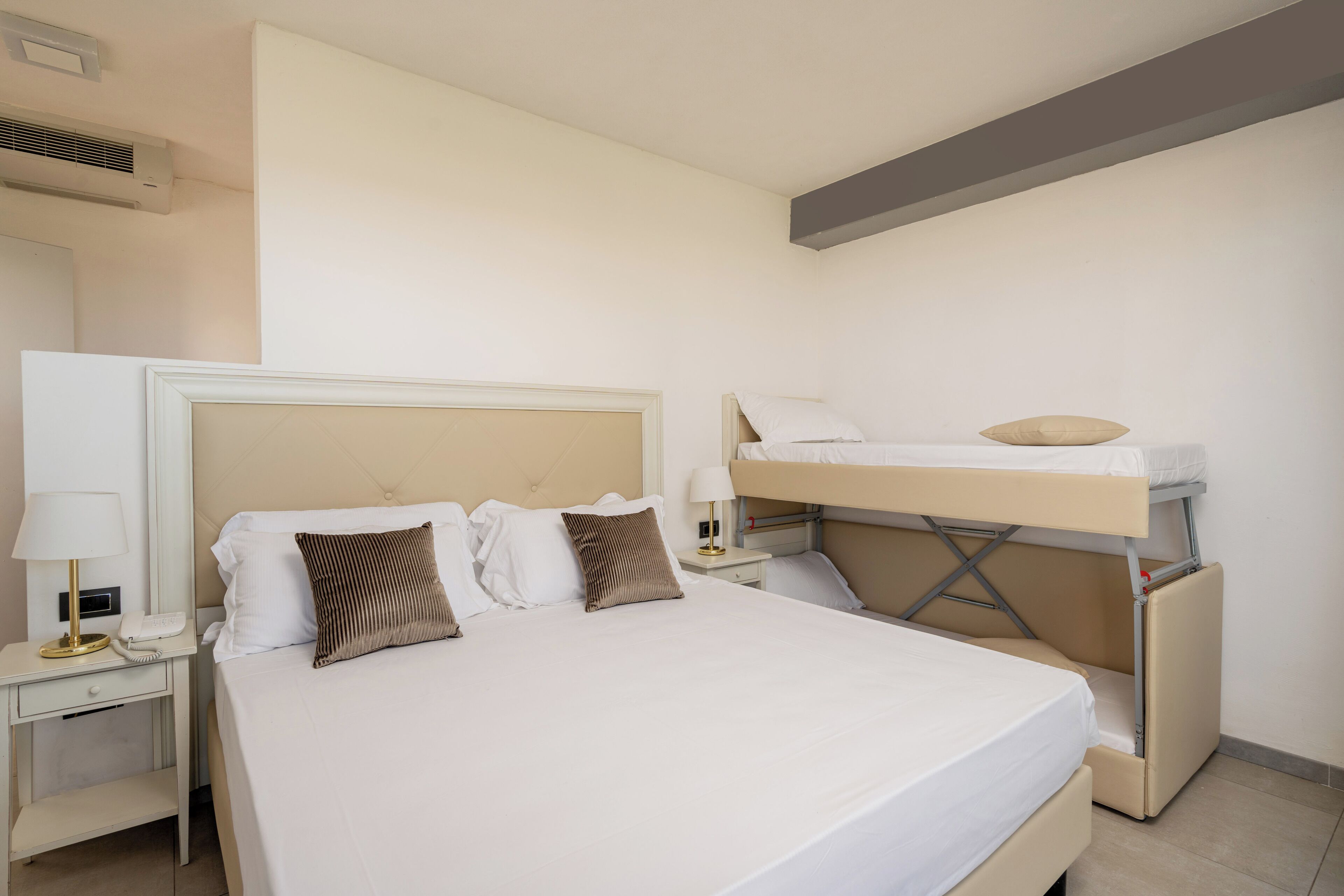 Ein Hotelzimmer mit einem großen Bett, einem Schreibtisch mit Lampe und einem Etagenbett.
