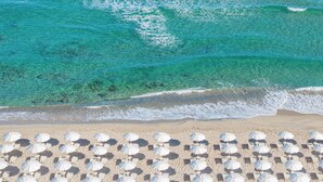 Una playa con aguas turquesas cristalinas y una hilera de sombrillas blancas.