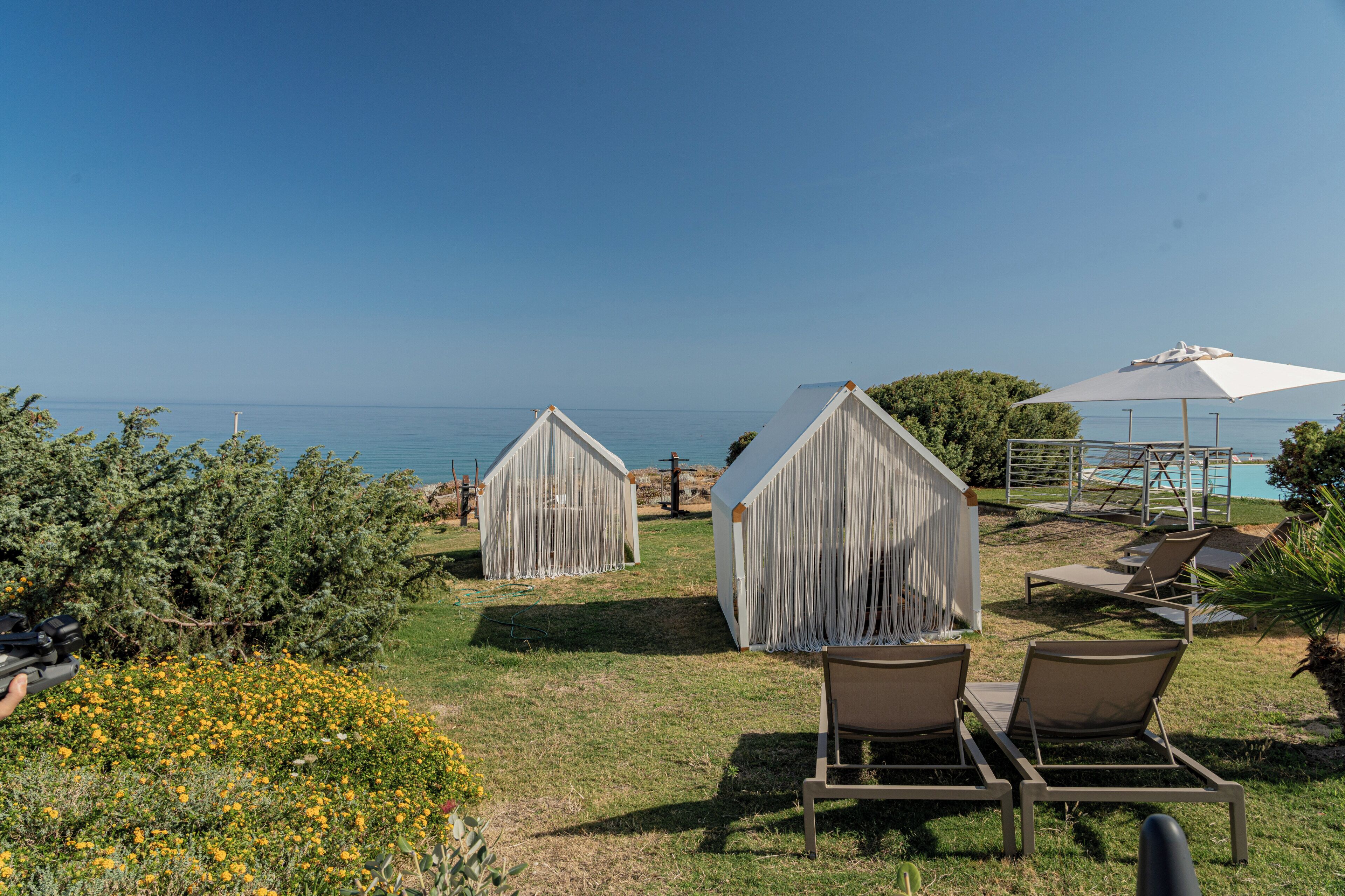 A coastal view with two covered structures, a pool area, and lounge chairs.