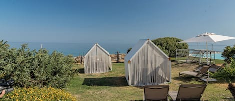 A coastal view with two covered structures, a pool area, and lounge chairs.
