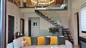 A modern living room with a sofa, a staircase, and a large window. - Villa ArGia with private pool & sea view (Apokoronas)