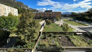 Un edificio moderno de varios pisos, rodeado de vegetación y un cielo despejado.
