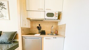Een kleine keuken met een magnetron, spoelbak en vaatwasser.