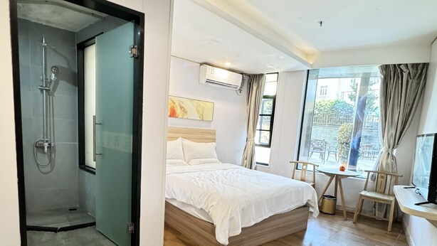 A modern hotel room with a large bed, a shower area, a small table, and a TV. - Zhuhai Dreamers Capsule Hotel (Zhuhai)