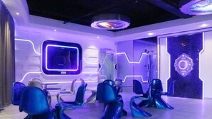 A futuristic lounge with neon-lit walls and blue chairs arranged in a semi-circle. - Zhuhai Dreamers Capsule Hotel (Zhuhai)