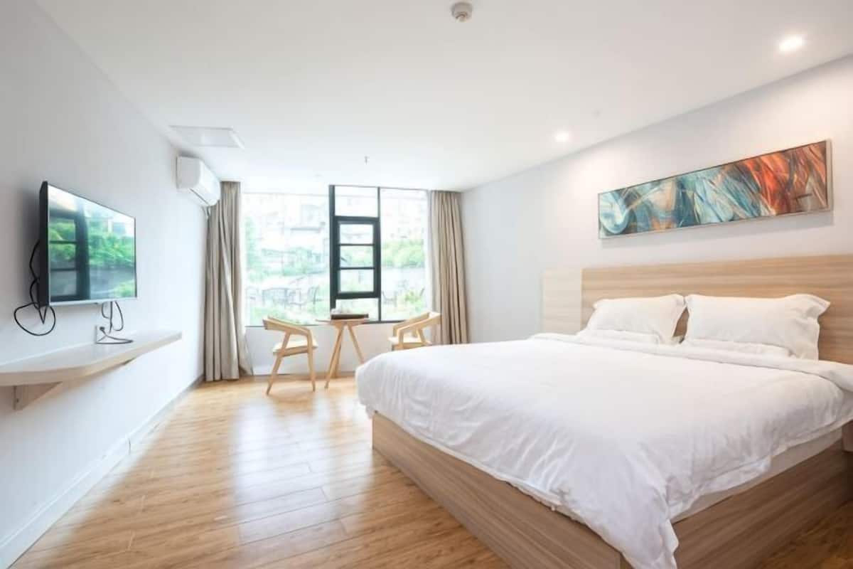 Ett modernt hotellrum med en stor säng, en platt-TV, ett skrivbord och ett fönster med gardiner.