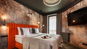 Un dormitorio moderno con pared texturizada, una cama grande con cabecero naranja, un televisor de pantalla plana montado en la pared y una ventana con cortinas.