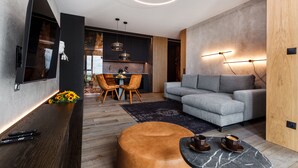 Una sala de estar moderna con un sofá gris, una mesa de centro de madera y un televisor montado en la pared.