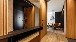 Un interior moderno con mostrador de madera, una zona de comedor con sillas y una pared oscura con lámpara.