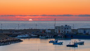 A coastal marina with boats docked, a clear sky, and buildings along the shore. - Asilah 32 (Asilah)