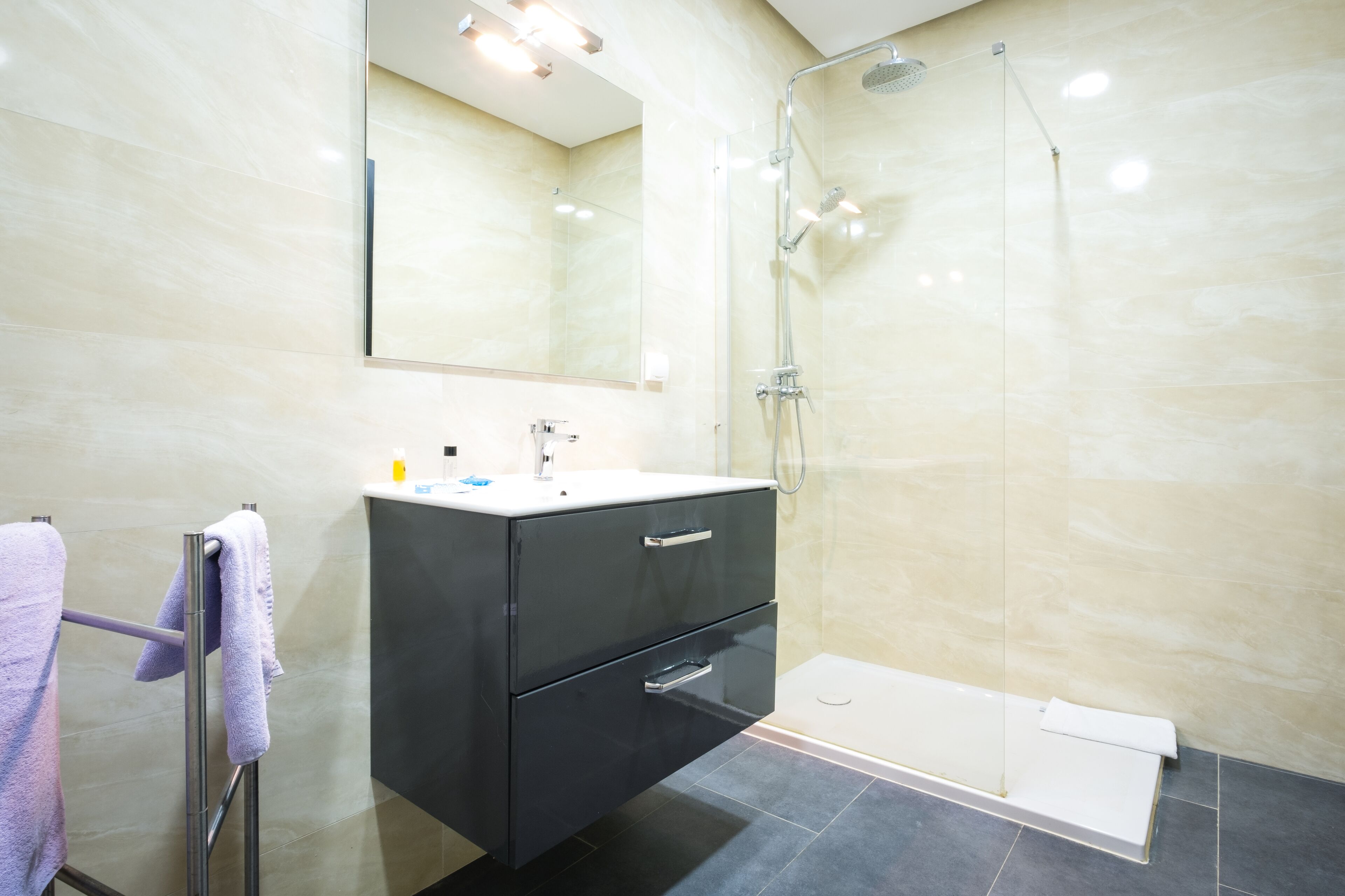 Un baño moderno con cabina de ducha de vidrio, tocador con espejo y bañera.