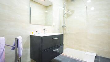 Un baño moderno con cabina de ducha de vidrio, tocador con espejo y bañera.