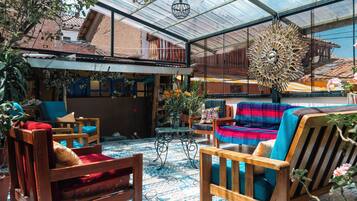 Un espacio interior amplio con techo alto, mobiliario de madera y una variedad de plantas.