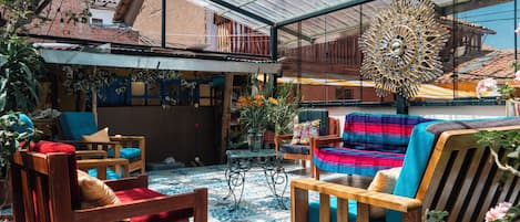 A spacious indoor area with a high ceiling, wooden furniture, and a variety of plants.