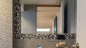 Un baño con un lavabo blanco, un espejo y un inodoro.