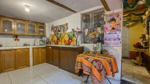 Una cocina con armarios de madera, piso de baldosas y una mesa con mantel colorido.
