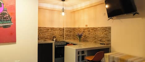 A compact kitchen with a built-in stove, a sink, and a small bar area.