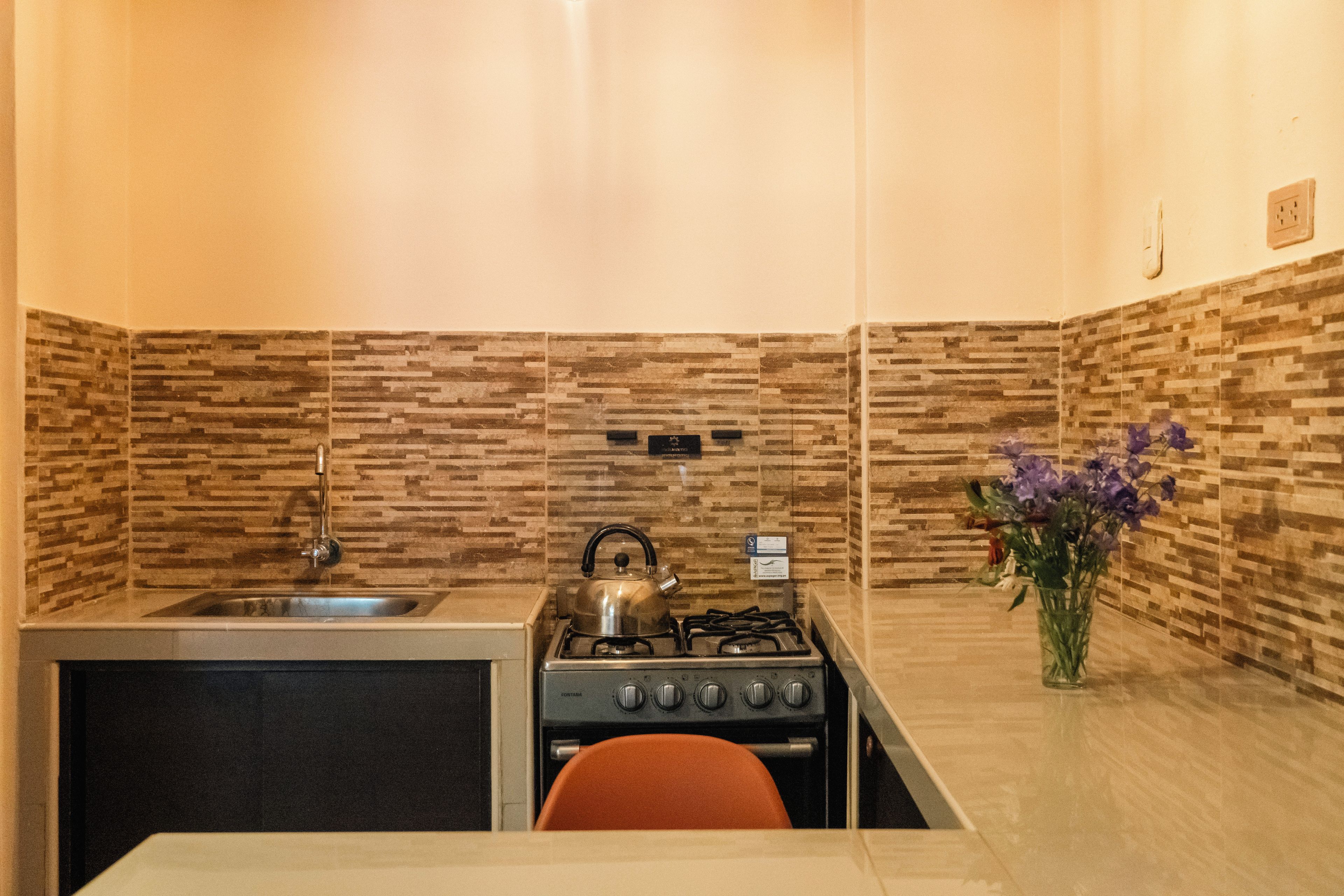 A compact kitchen with a gas stove, a sink, and a tiled backsplash.
