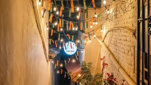 Un callejón estrecho con luces decorativas y un letrero de neón.
