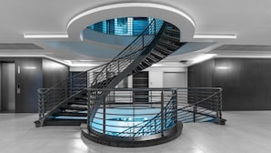 Een moderne spiraaltrap met een glazen omheining bovenop, omgeven door een rond platform.