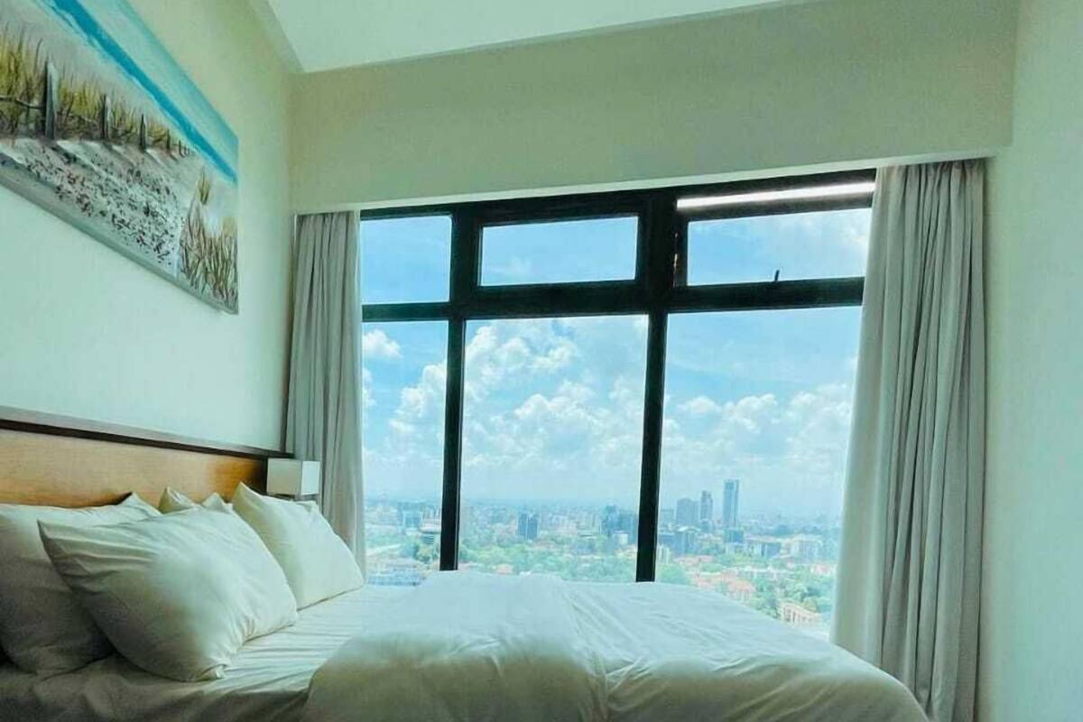 Una habitación de hotel con una cama grande, vistas de la ciudad a través de ventanales del suelo al techo y un cuadro en la pared.