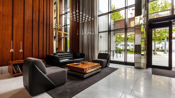 A modern living room with a sofa, armchairs, a coffee table, and a bookshelf. - Brabank Residence by HappyStay (Gdansk)