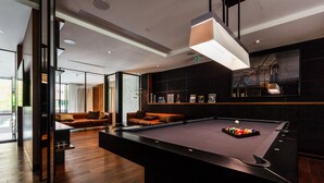 A modern pool table in a well-lit room with a sofa and a large window. - Brabank Residence by HappyStay (Gdansk)