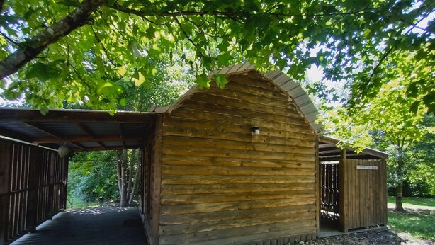 Een houten chalet met een schuin dak, een klein terras en een grindpad.