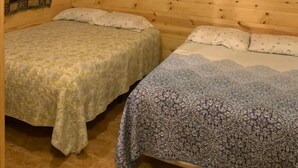 Een blokhut met twee bedden, houten wanden en een lijst met een luipaard erop.