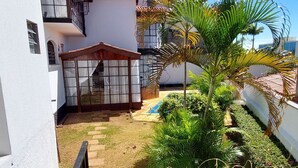 A courtyard with a white building, a small garden, and a palm tree. - Amplo estudio proximo ao BOS em Sorocaba (Sorocaba)
