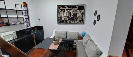 A compact living space with a kitchenette, a sofa, a coffee table, and a dining table.