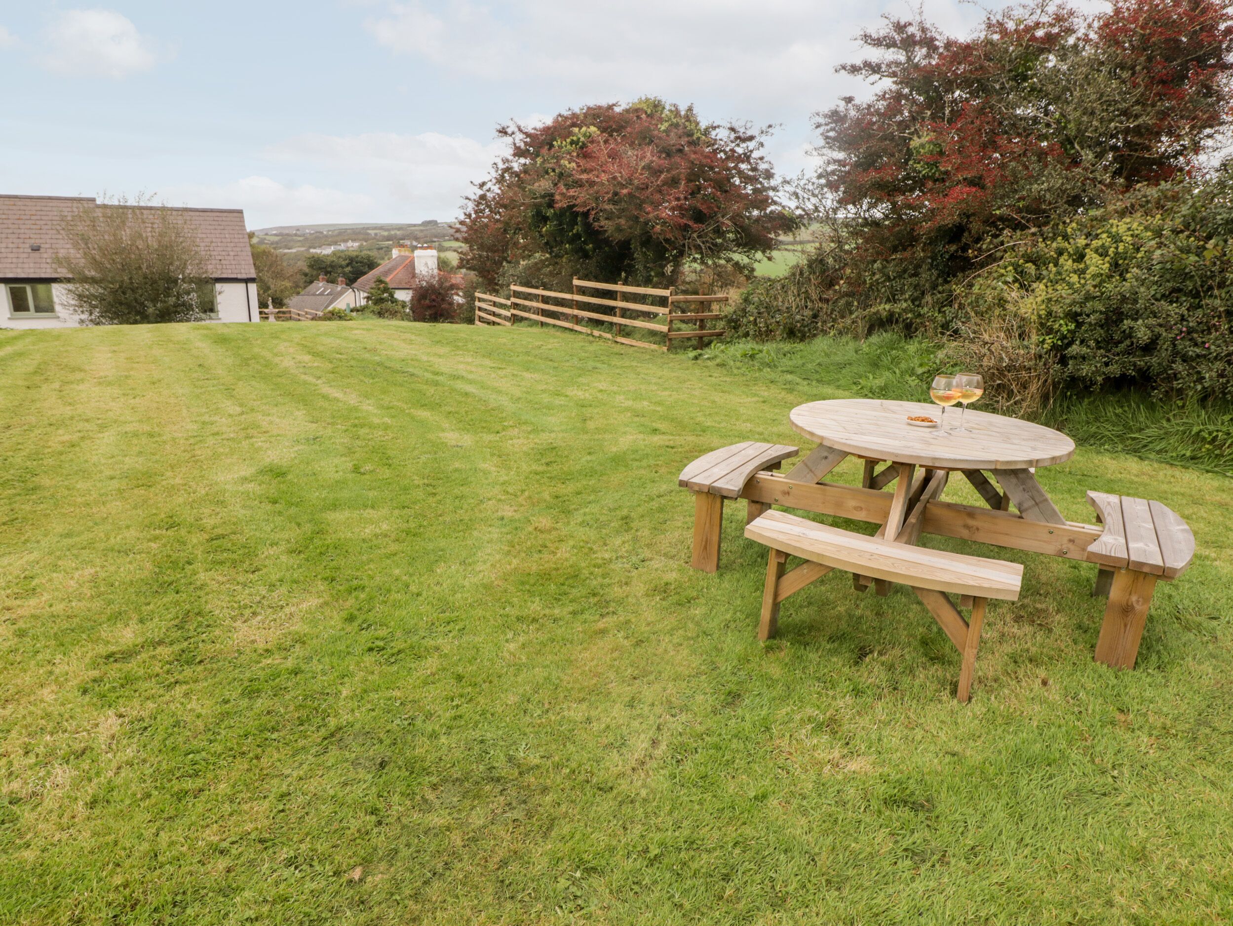 A wooden picnic table with benches in a grassy backyard.