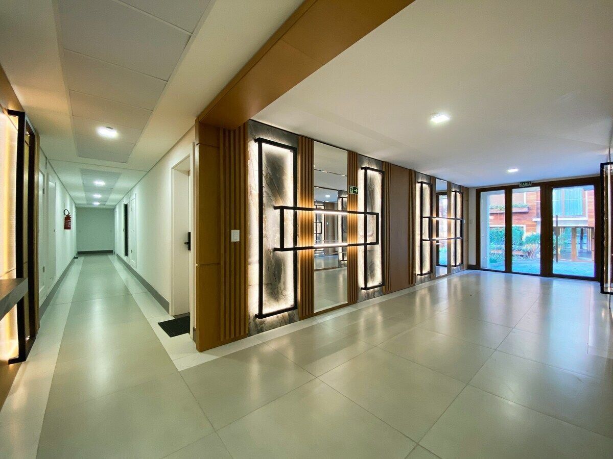 Un corridoio d'hotel spazioso dal design moderno, caratterizzato da un lungo percorso con porte su un lato e ampie finestre sull'altro.