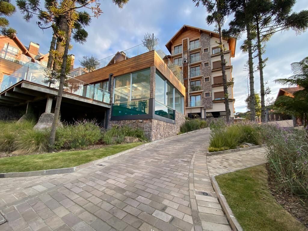 Un edificio moderno con fachada de vidrio, un sendero de piedra y abundante vegetación.