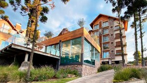 Un edificio moderno a più piani con ampie vetrate, facciata in pietra e un vialetto lastricato che conduce all'ingresso.
