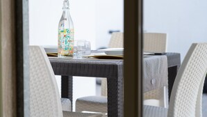 A wicker table with a bottle and glasses, and wicker chairs. - Appartamento Murena 8 (Squinzano)