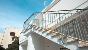 A white building with a metal balcony railing and a satellite dish on the roof. - Appartamento Murena 8 (Squinzano)