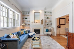 Un salón con un sofá azul, una chimenea y estanterías.
