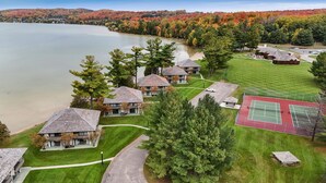 A lakeside residential area with multiple houses, a tennis court, and a gazebo.